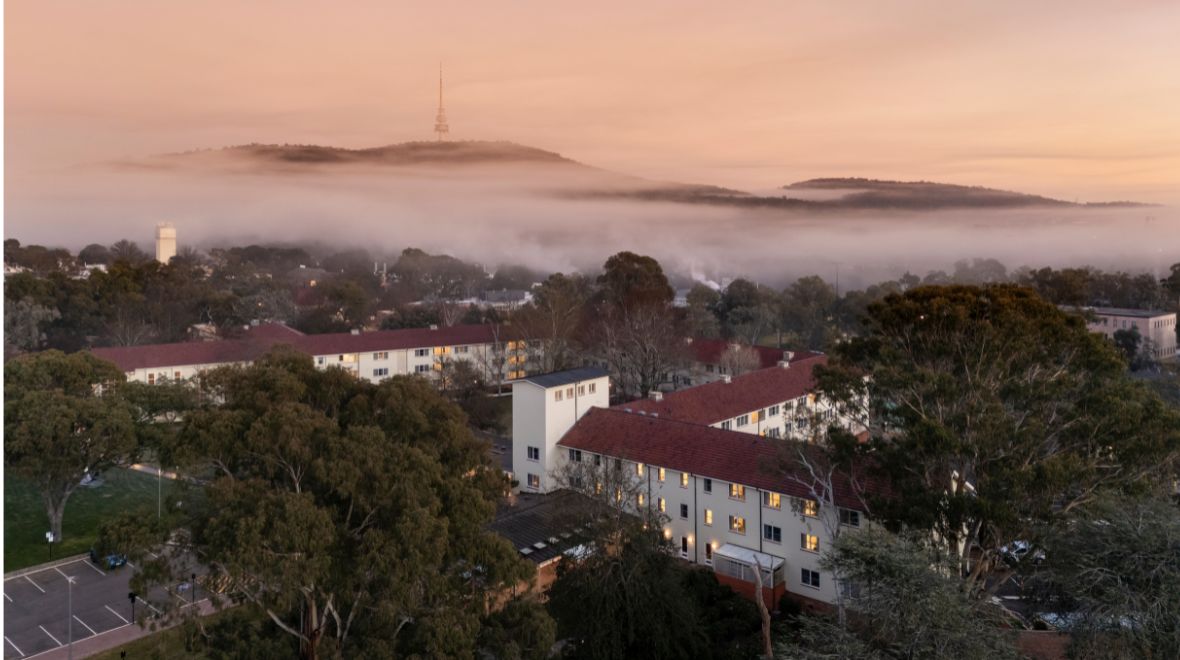 Aerial view of University House in Canberra with fog and Telstra tower in the background.