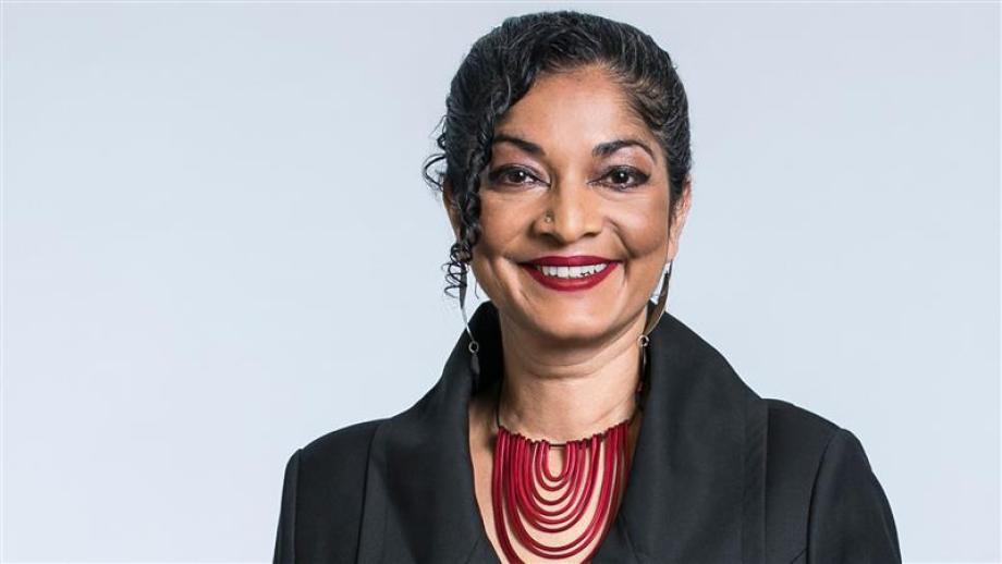 Close-up of Padma Raman. She is smiling and wearing a red shirt and a black jacket.