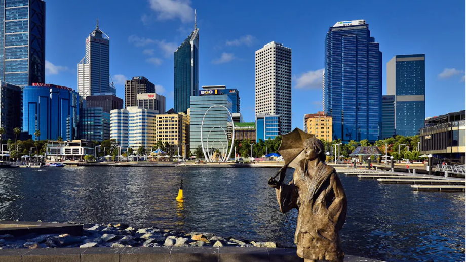 Female statue on the waterfront with a city skyline behind her