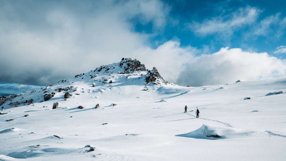 Two skiers climbing up a mountain covered in snow