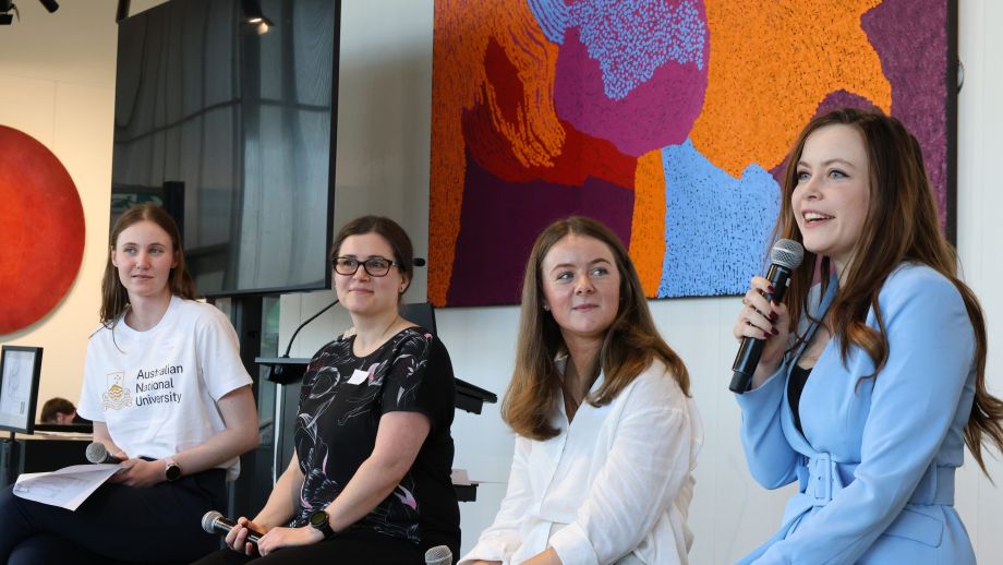 Three panelists speaking, ANU facilitator sitting at the side.