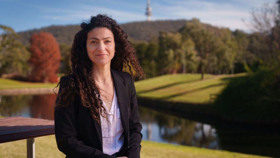 A woman sitting on a bench smiles to the camera.
