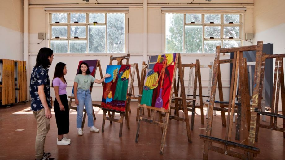 Three people standing in a room with artworks