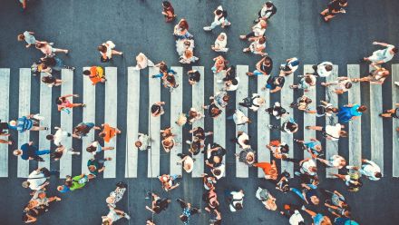 An aerial view of a crowd of people crossing a pedestrian crosswalk