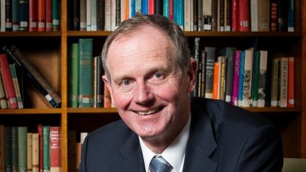 Picture of Graham Tuckwell smiling in front of bookshelf