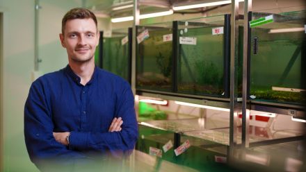 Dr Ivan Vinogradov has his arms crossed and is standing in front of fish tanks in a science lab