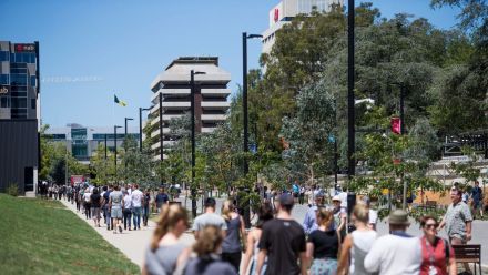A crowd of people walk along University Avenue at the Australian National University.