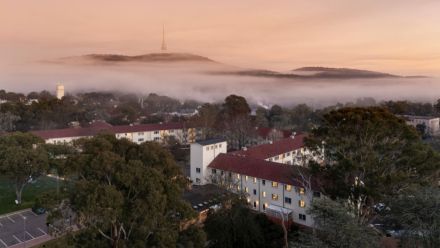 Aerial view of University House in Canberra with fog and Telstra tower in the background.