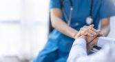 A nurse holds a senior patient's hand. 