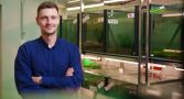 Dr Ivan Vinogradov has his arms crossed and is standing in front of fish tanks in a science lab