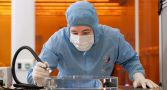 Technical officers manoeuvre glass substrate prior to polishing in the ANU Research School of Physics cleanroom.