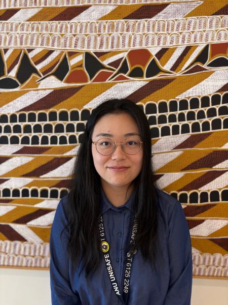 A person with long black hair standing in front of artwork