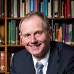 Picture of Graham Tuckwell smiling in front of bookshelf