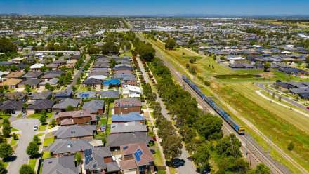 An aerial view of homes and a train track to the right of the photo