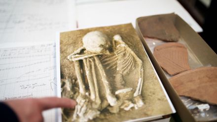 A finger points to a photograph of mummified bones